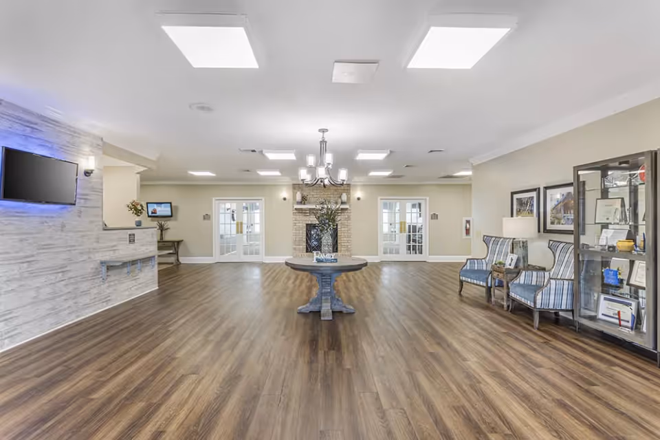 Interior view of the lobby at Brookdale Grayson View, featuring a wooden floor, a round table with a plant, and comfortable seating areas.