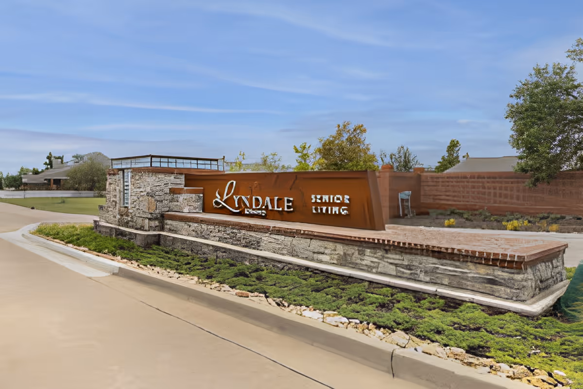 Stone and metal entrance monument sign reading "Lyndale Senior Living" beside a driveway with landscaping.