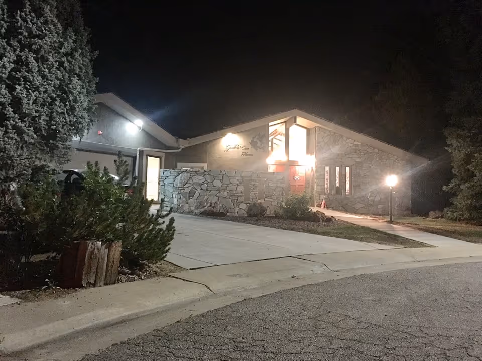 Night view of Gardens Care Senior Living building exterior with stone facade and illuminated entrance.