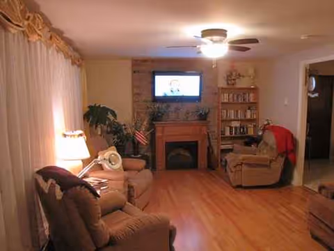 Cozy living room with fireplace, TV, bookshelf, and multiple recliners.