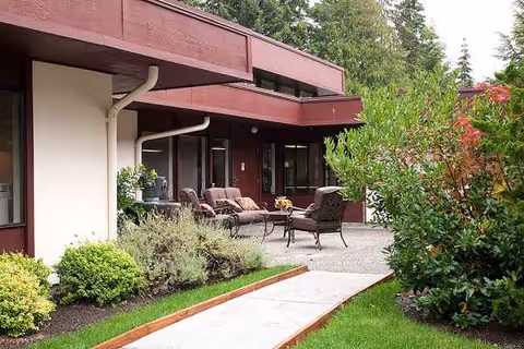Exterior view of Aldercrest Health & Rehab Center with patio seating and landscaping.