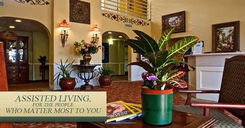 Assisted living lobby with seating, plants, decorative artwork and a promotional sign.