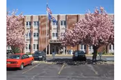 Front view of Cedarbrook Fountain Hill building with pink blossoming trees and parked cars.
