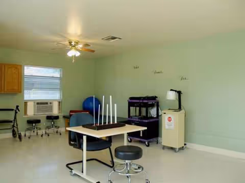 Mint-green activity room with exercise gear, stools, and a ceiling fan.