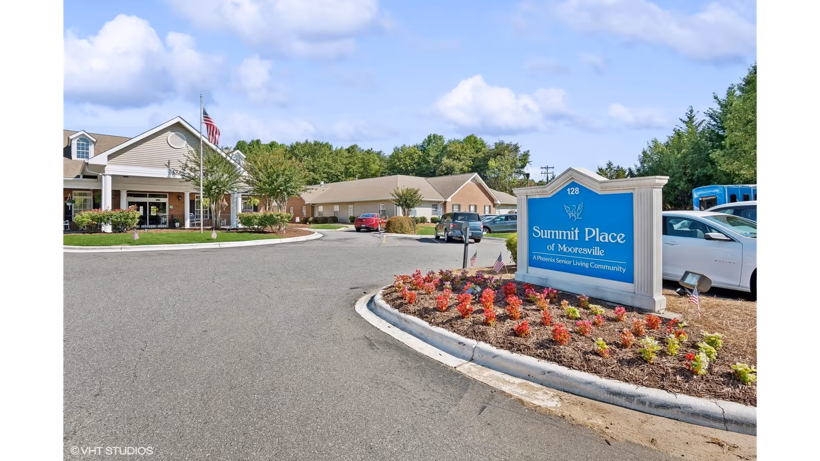 Entrance driveway with landscaped flower bed and a blue sign reading "Summit Place of Mooresville" in front of the senior living building.