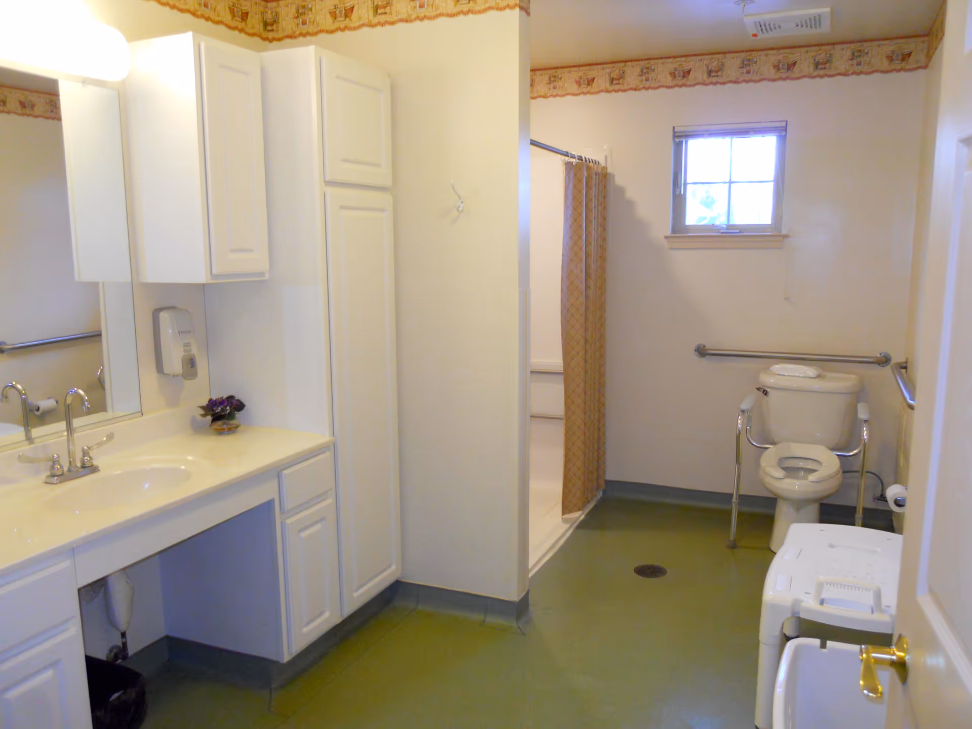 Accessible bathroom with a sink and cabinets, walk-in shower with curtain, and a toilet with grab bars.
