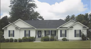 Single-story building with a central front entrance, shutters, and well-kept shrubs.