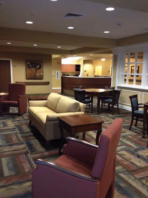 A lounge area with beige sofa, chairs, tables, and a reception desk.