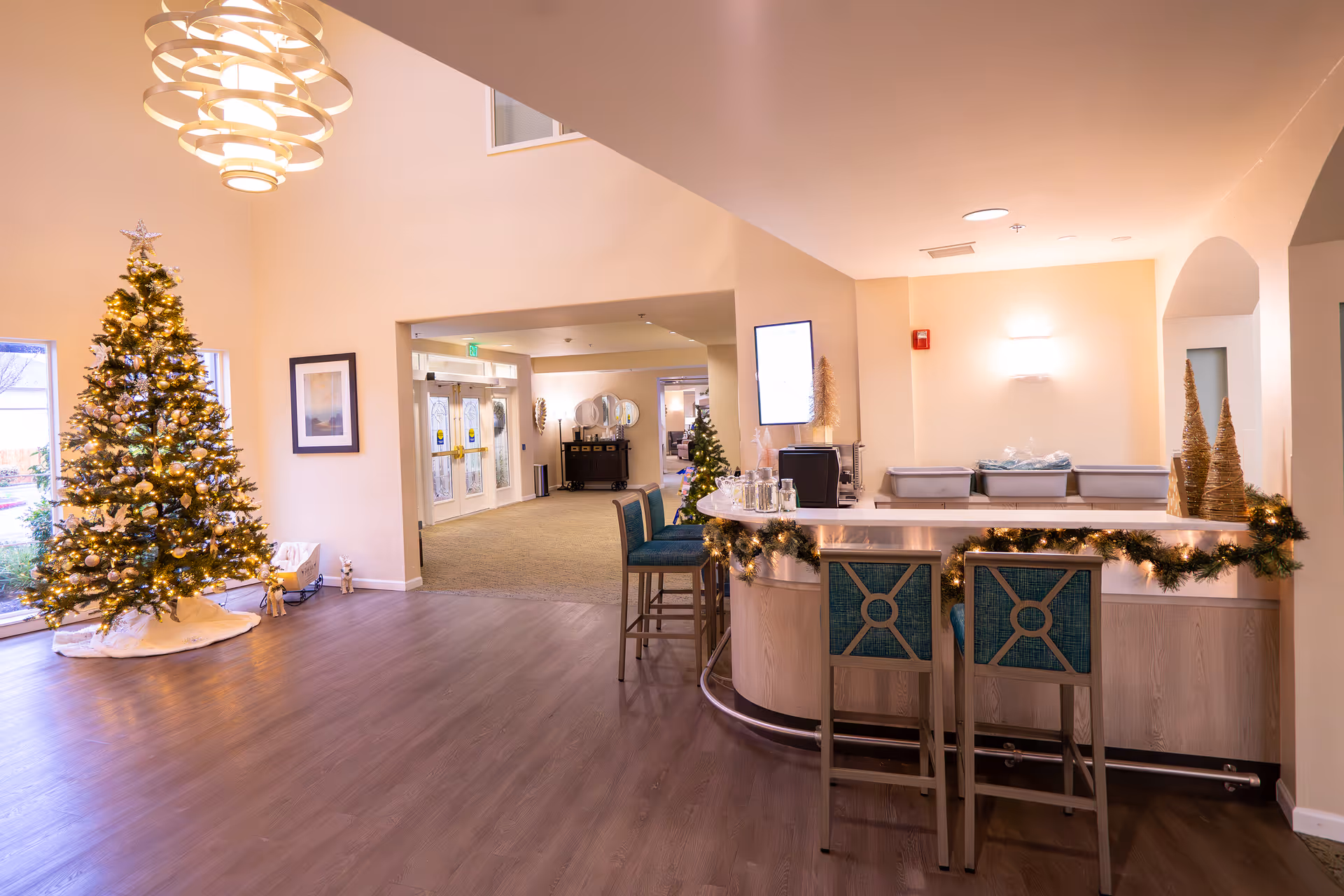 Bright reception lobby decorated for Christmas with a lit tree, a curved front desk with bar stools, and festive garlands.