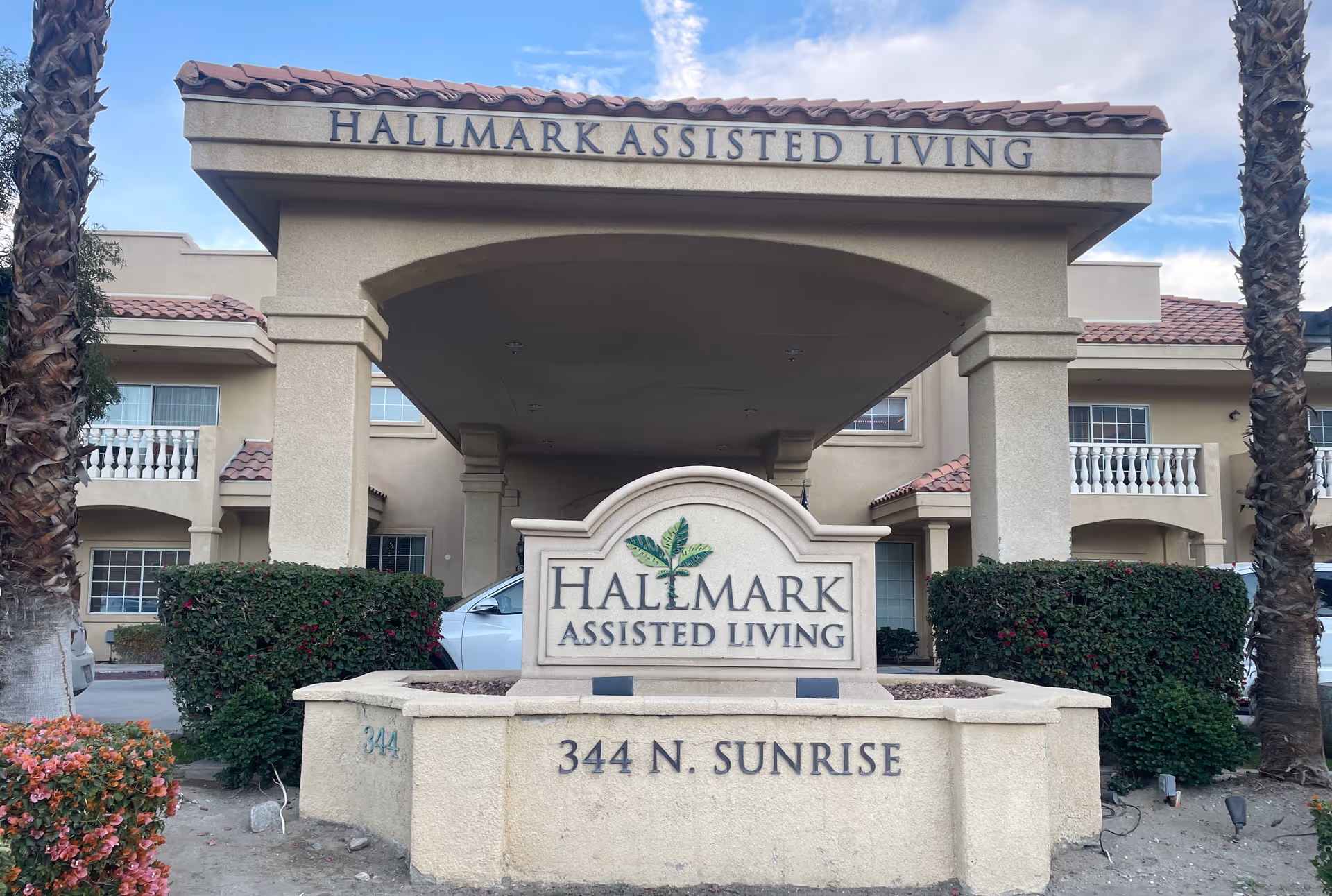 Exterior front entrance of Hallmark Assisted Living with a stone sign reading 'Hallmark Assisted Living' and the address 344 N. Sunrise.