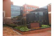 Exterior view of a modern facility with glass entrance and landscaped brick planters.