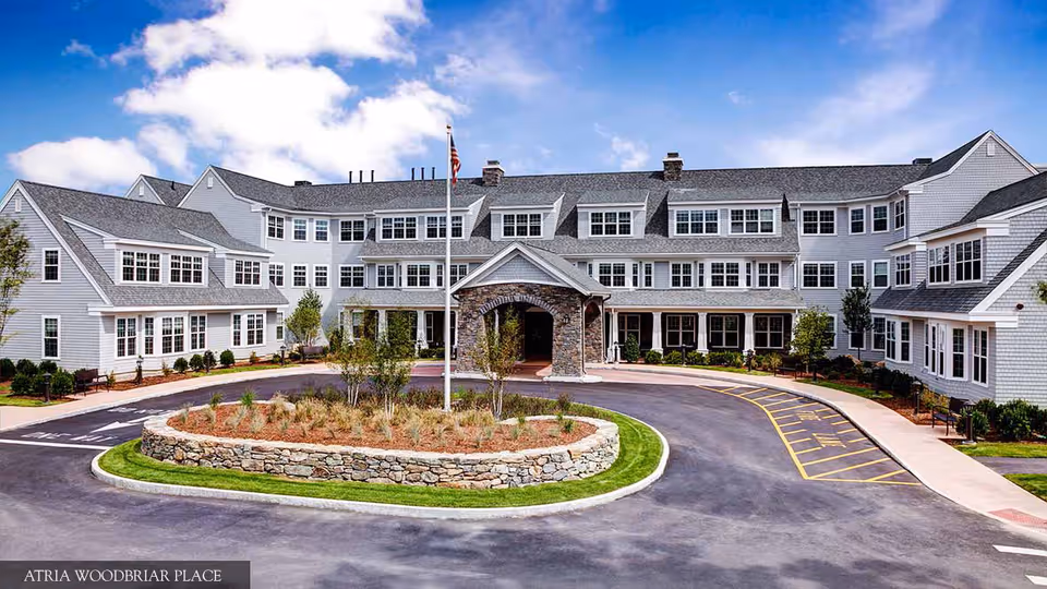 Atria Woodbriar Place exterior building with circular driveway and stone entrance.