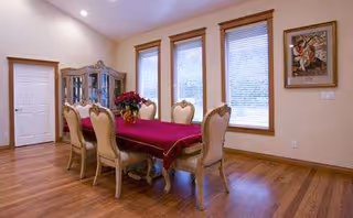 A dining room with a long table draped in red cloth and beige chairs.