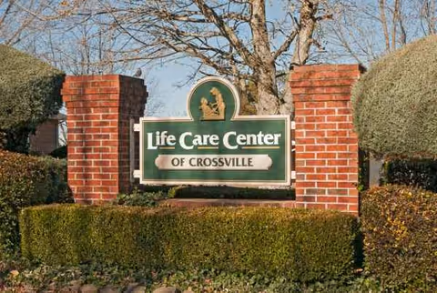Entrance sign for Life Care Center of Crossville surrounded by brick pillars and hedges.