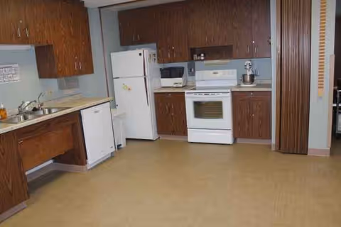 Old-fashioned kitchen with brown cabinets, white appliances, and a tile floor.