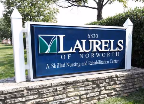 Blue sign reads Laurels of Norworth on a stone wall at the facility entrance.