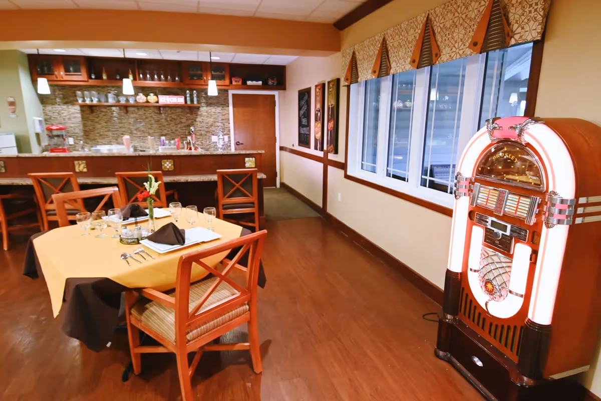 Dining room with a set table, bar counter and a lit vintage jukebox along the wall.