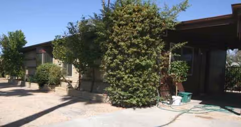 Exterior view of a senior facility with trees and a shaded entry area.