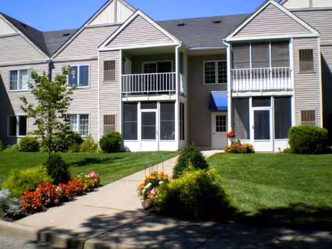 Exterior of Harrogate Retirement Community, two-story building with balconies, green lawn, and flower beds.