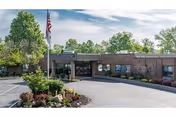 Front view of Legacy Barberton senior living facility with flag and landscaping.
