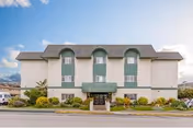 Three-story beige nursing facility with green entrance awning and landscaped front.