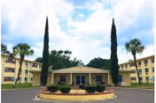 Front exterior of Campus Towers, a U-shaped senior living facility with palm trees and circular drive.