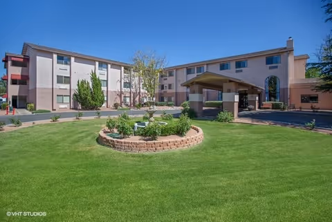 Exterior view of Cottonwood Village senior living with a circular brick planter and green lawn.