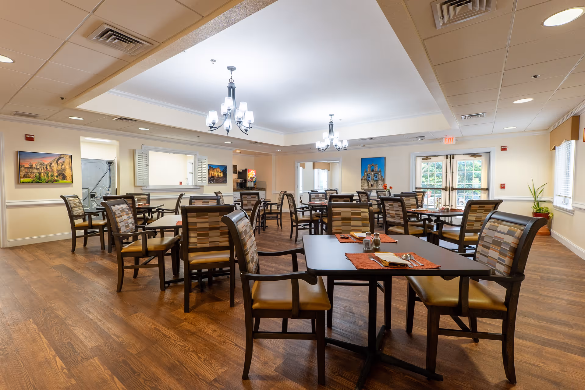 Interior view of the dining room at Gemstone Senior Living at Castle Hills, featuring tables and chairs arranged for dining, with decorative artwork on the walls and natural light coming through the windows.