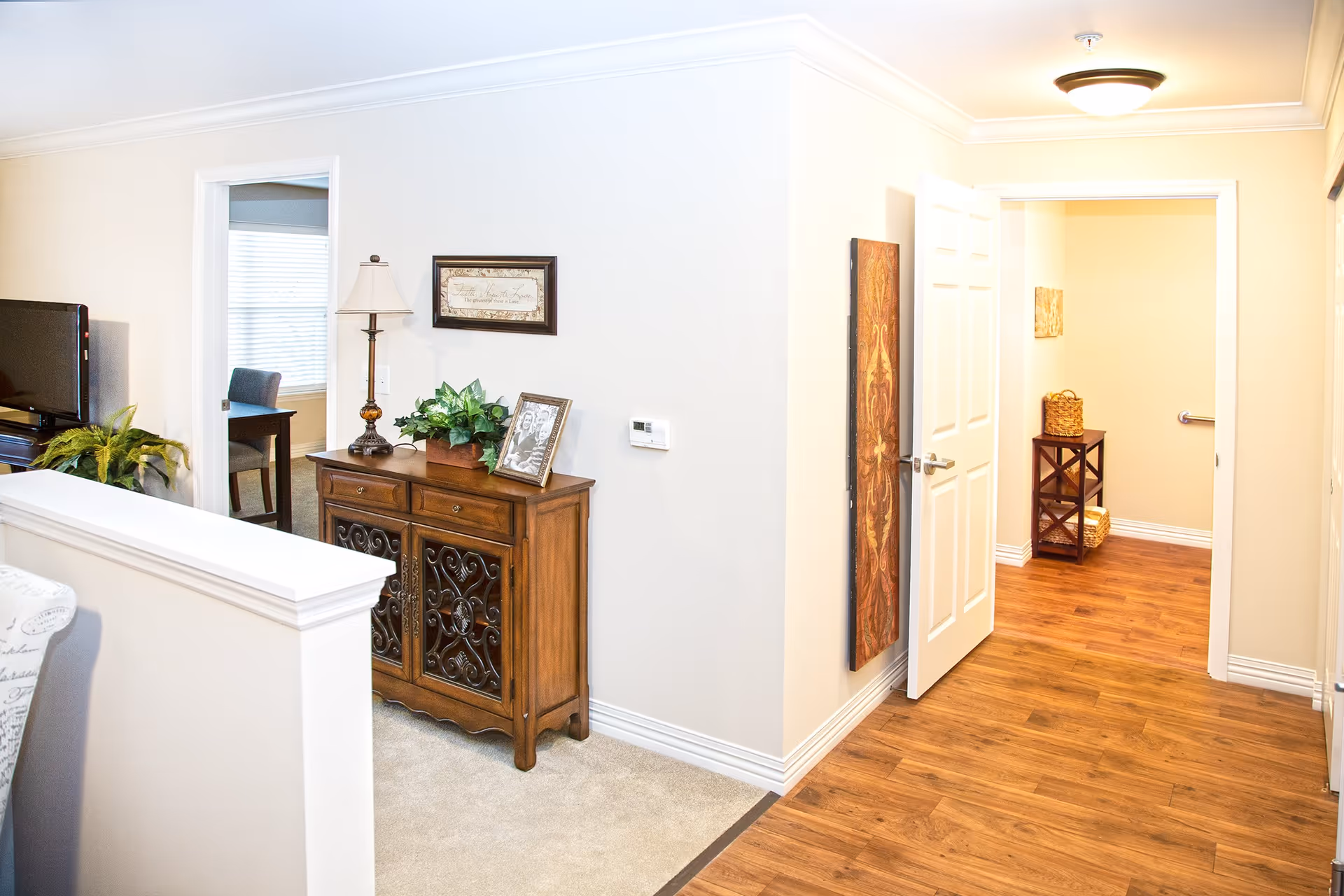 Bright interior hallway and living area featuring a wooden console table, open doorway, and wood floors.