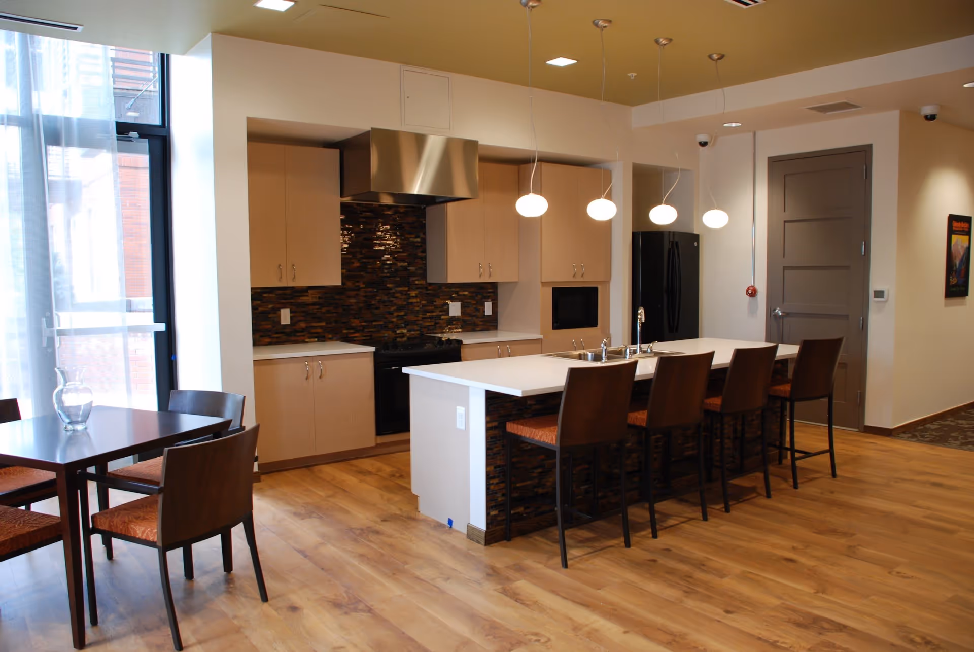 Modern open kitchen and dining area with a long island, pendant lights, bar stools, and a small dining table.