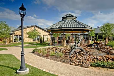 Outdoor courtyard of a senior living facility with gazebo, stone landscaping, and a path.
