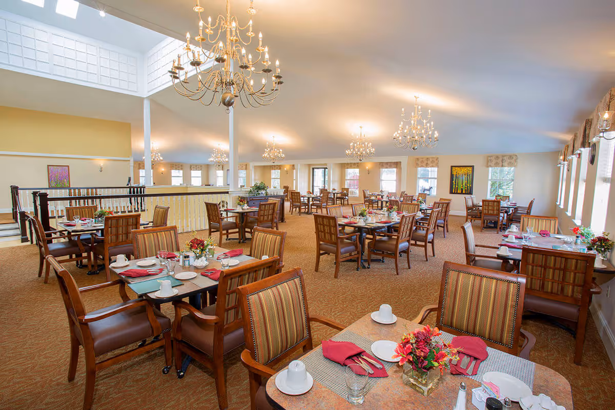 Spacious, well-lit dining room with multiple set tables, chandeliers, and large windows.