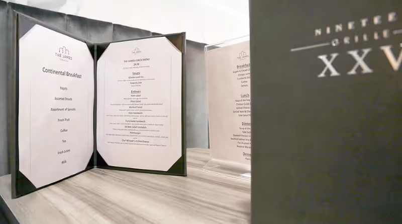 Tabletop display of folded dining menus from The James Ferndale on a wood surface beside a black menu cover.