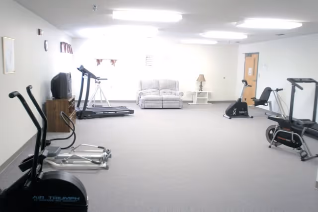 Spacious indoor fitness room with treadmills, bikes, and a small seating area.