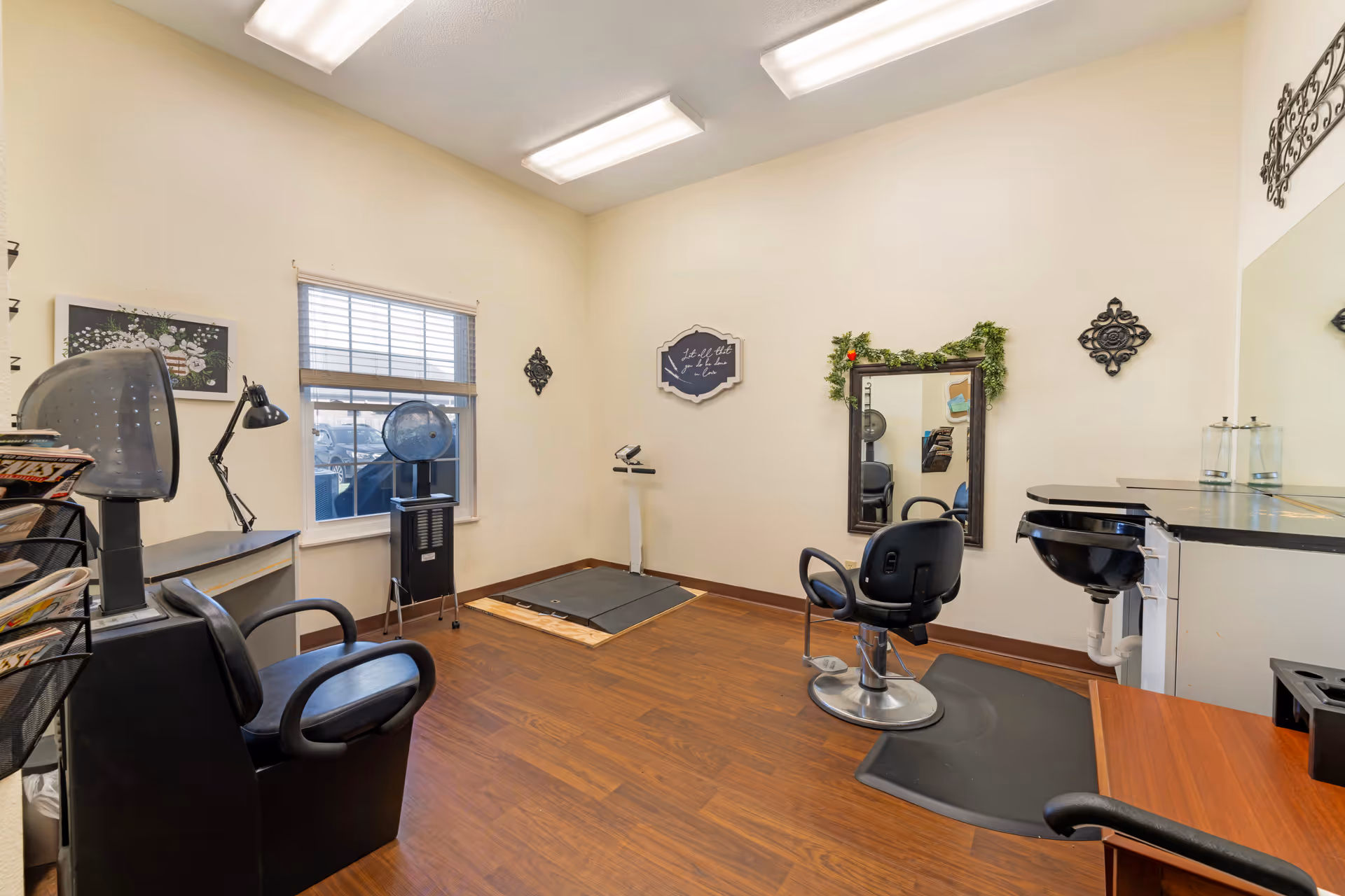 Small salon room with styling chairs, mirrors, a wash sink and wooden floors.