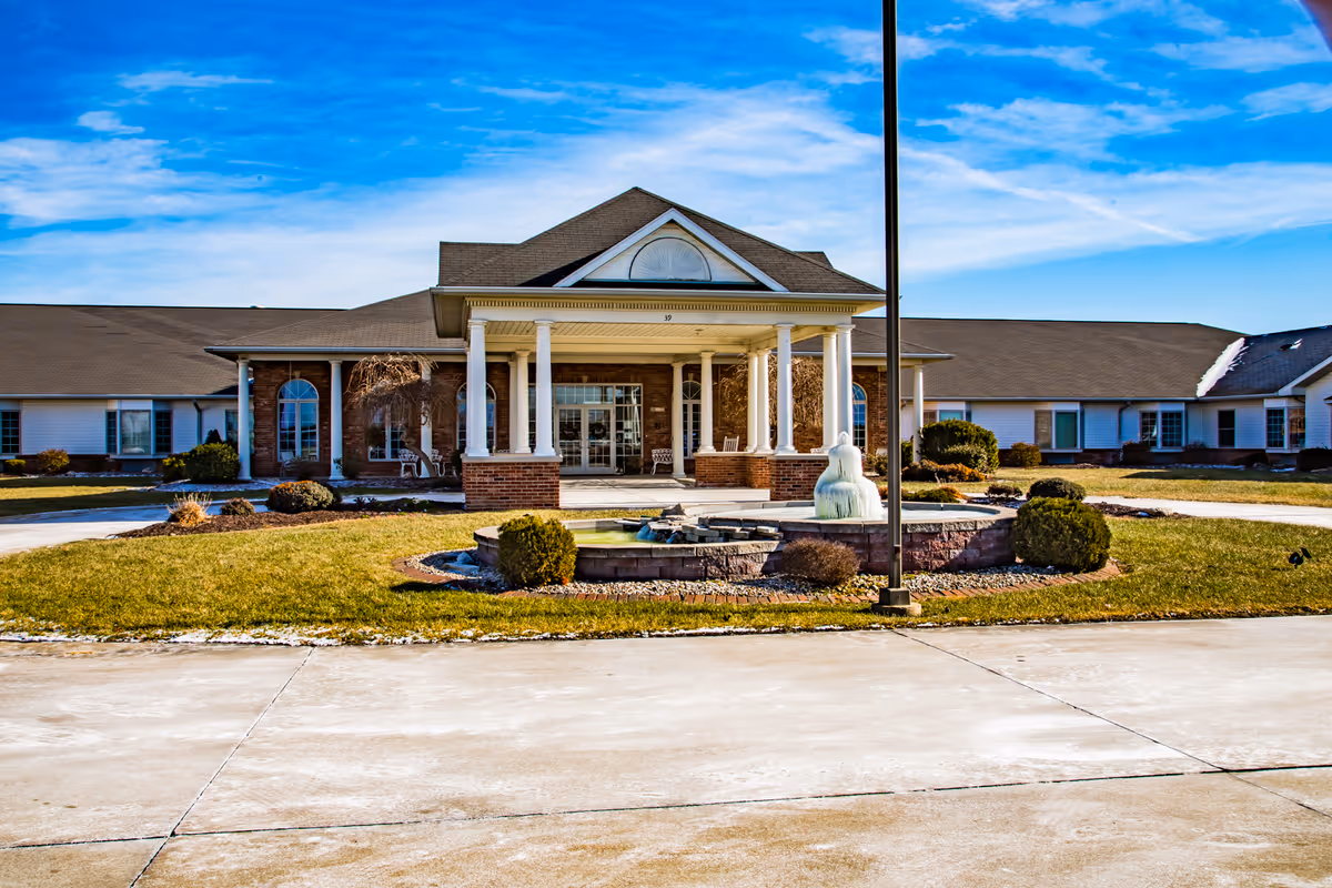 Front view of Charter Senior Living of Troy with fountain and entrance columns.