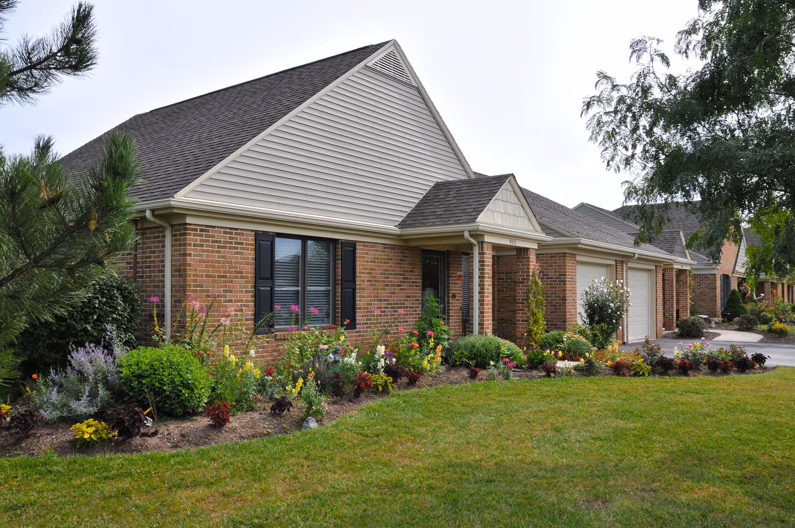 Single-story brick residence with a landscaped front garden and attached garages.
