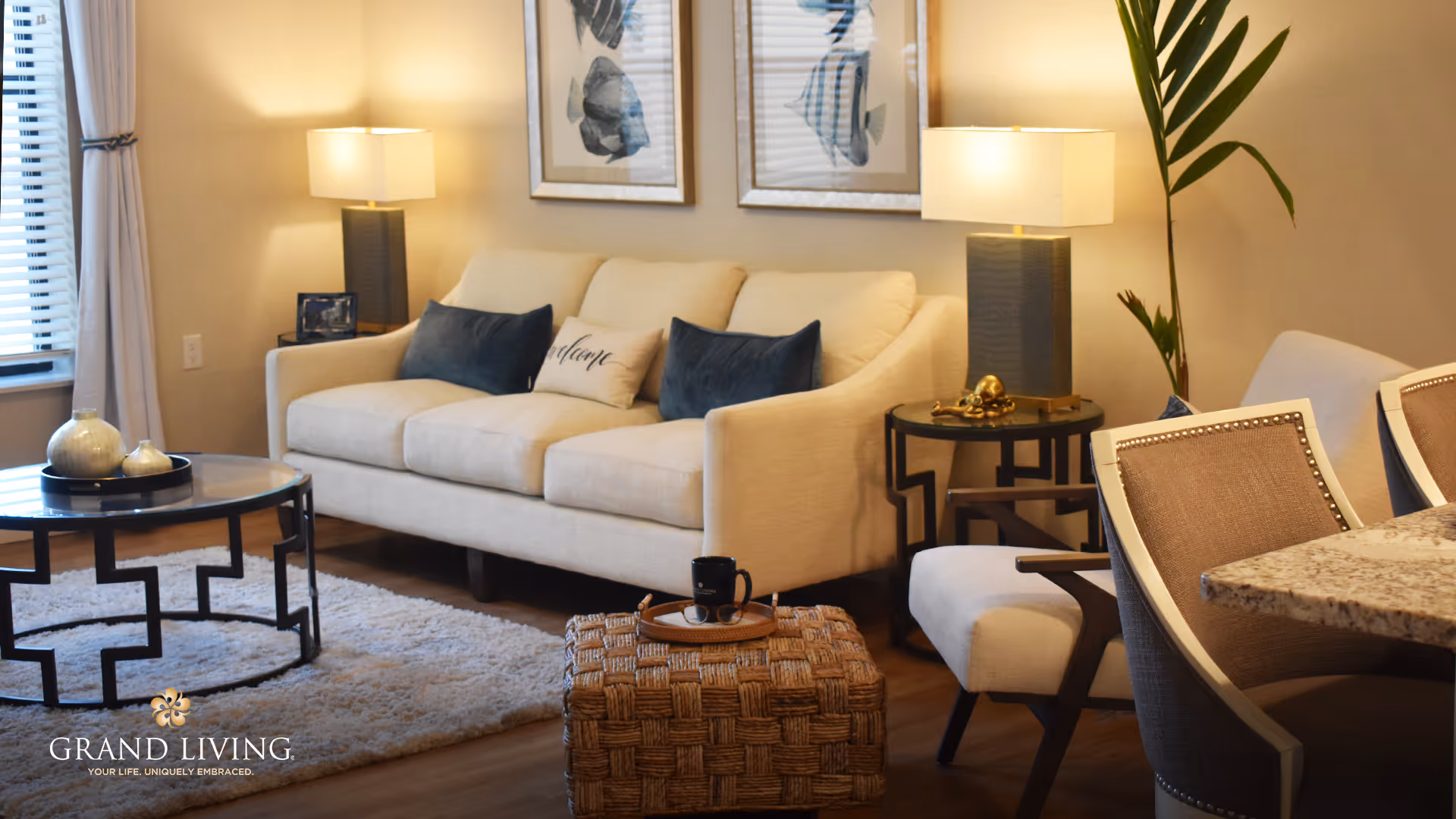 Bright, stylish living room with a beige sofa, coffee table, lamps, accent chairs and decorative pillows.