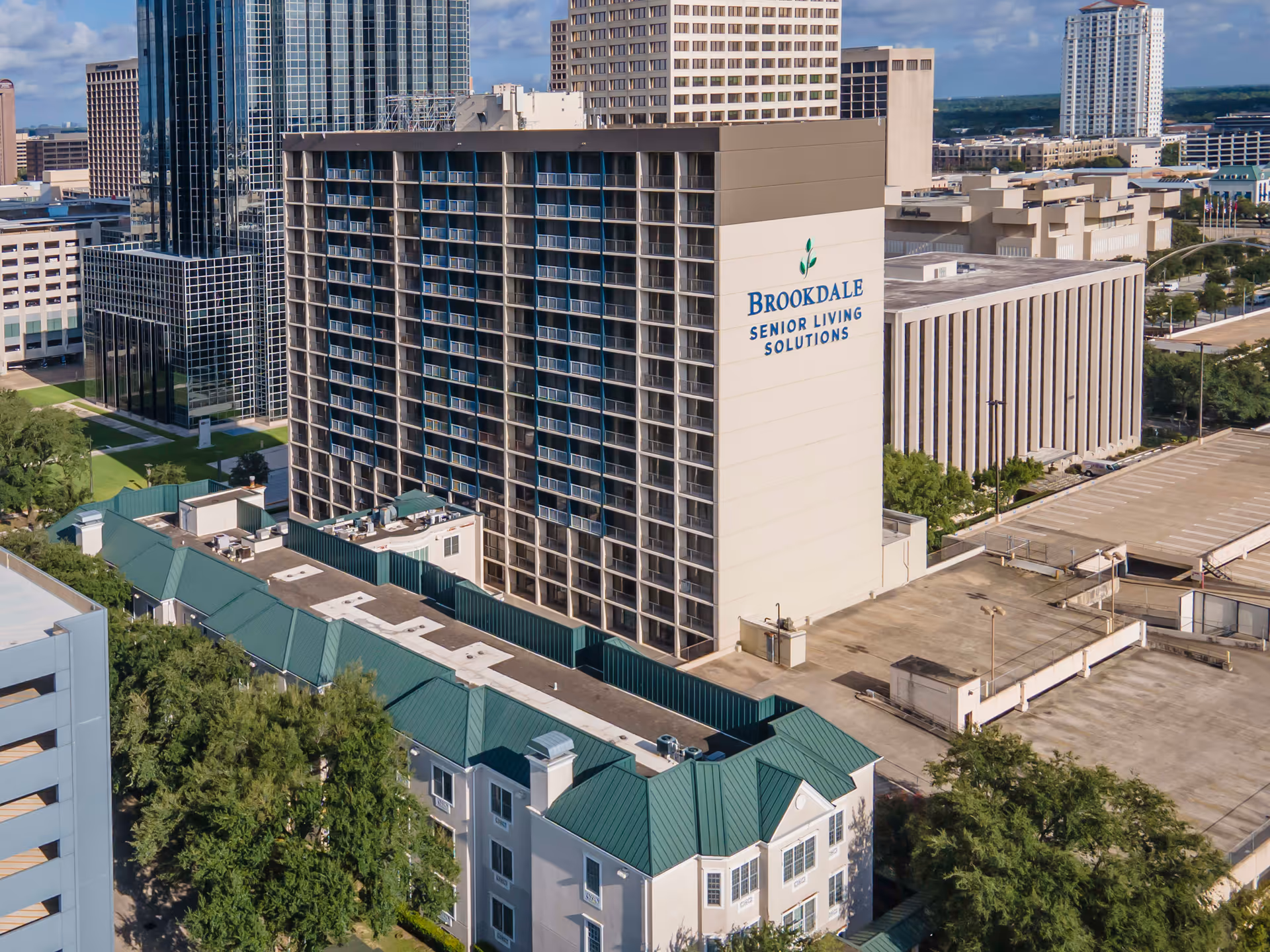 Aerial view of the Brookdale Senior Living high-rise building with rows of balconies and surrounding rooftops in a downtown area.
