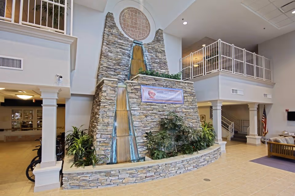 Lobby interior showing a large tiered stone water feature with plants, seating area, and an upstairs balcony.