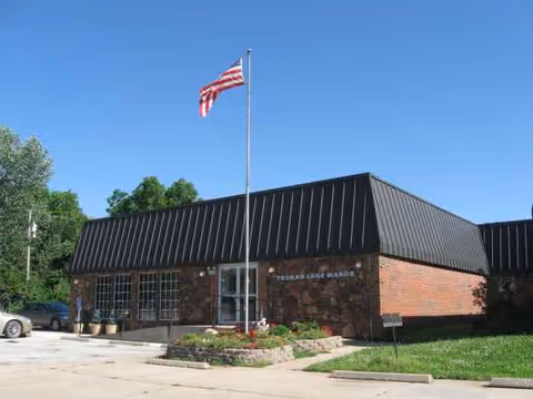 Front of Truman Lake Manor, brick building with flagpole and blue sky.