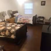 Bedroom with two twin beds with floral bedspreads, a nightstand, lamps and a window.