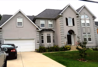 Front view of a two-story beige assisted living home with a garage and green lawn.