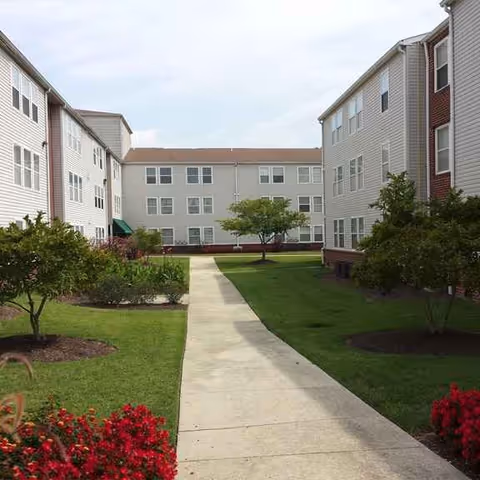 Exterior view of a senior living campus with central walkway and manicured lawn.