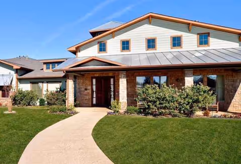 Front exterior of a stone-and-brick senior living facility with a curved walkway.
