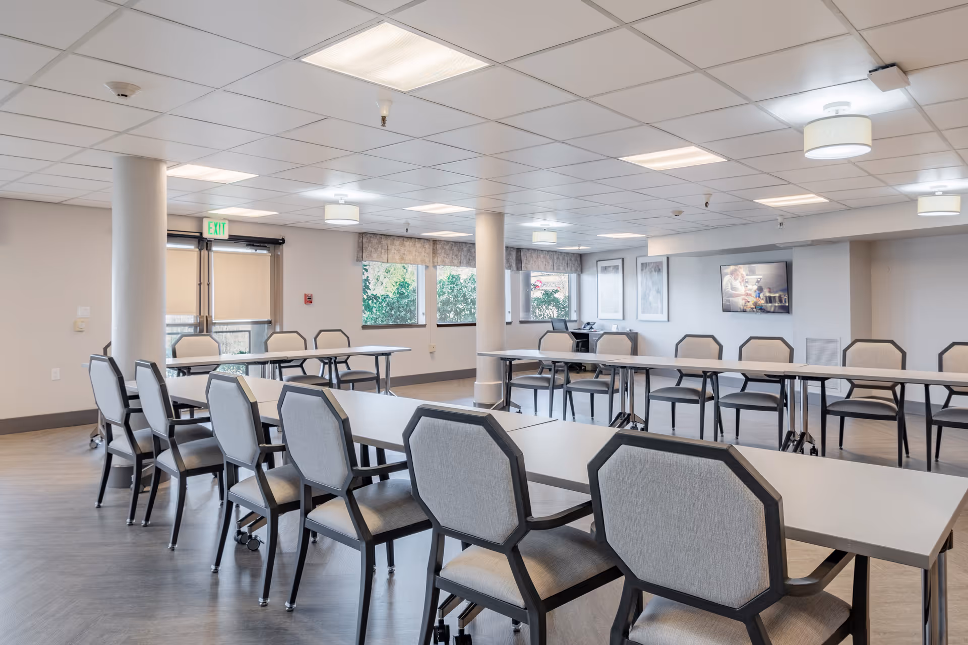 Spacious multipurpose dining/activity room with rows of tables and chairs, windows, and neutral decor.