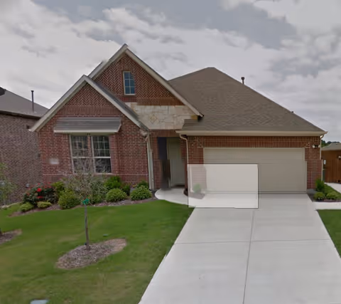 Front exterior of a single-story brick house with an attached two-car garage, concrete driveway and small lawn.