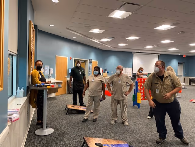 A group of staff members interacting in a recreational room at a senior living facility.
