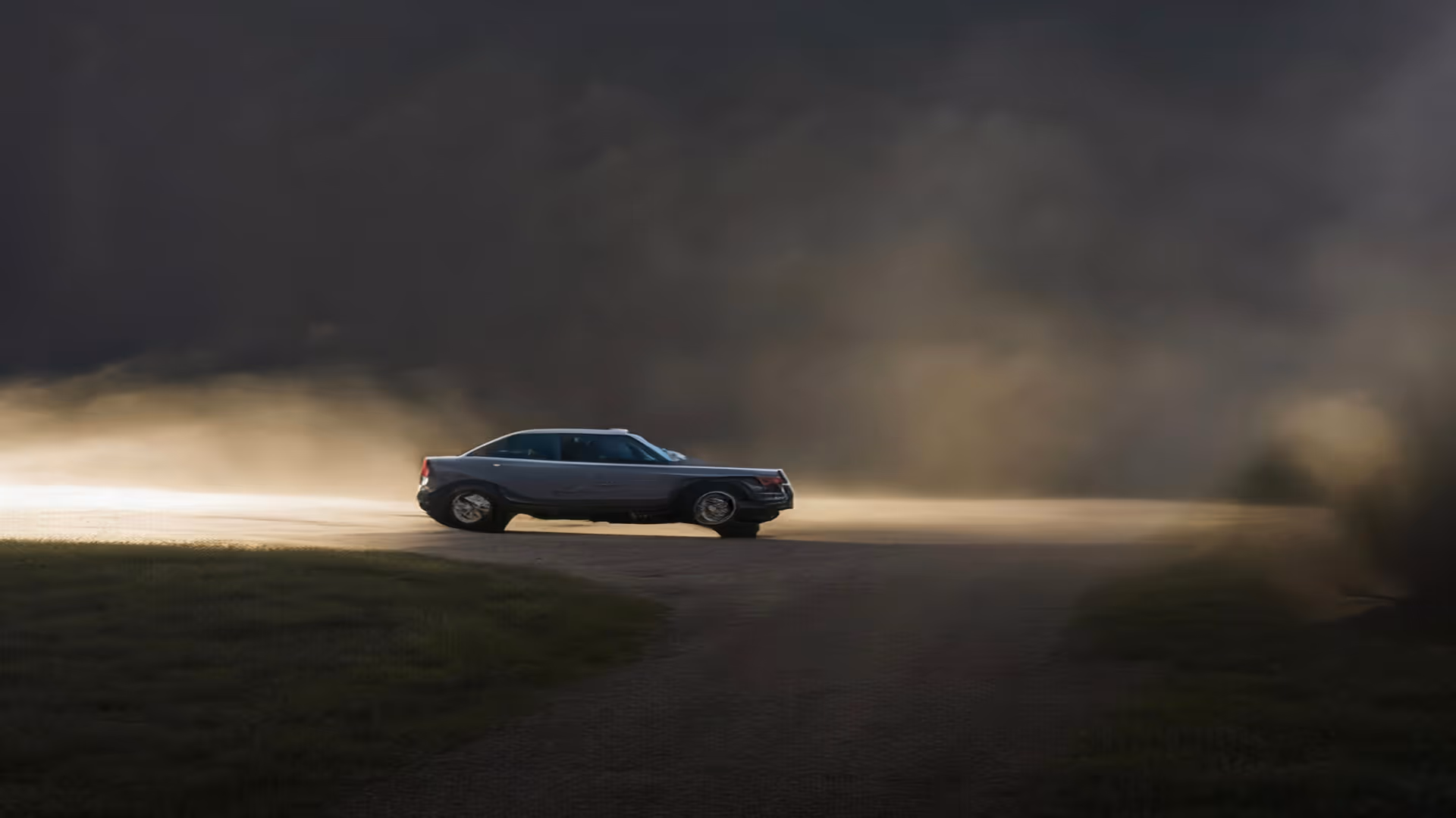 A lone sedan driving on a foggy road under a dark, moody sky.