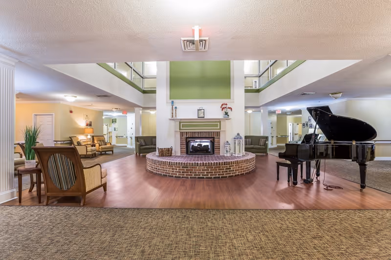 Spacious communal lounge with a central brick fireplace, seating areas and a grand piano.